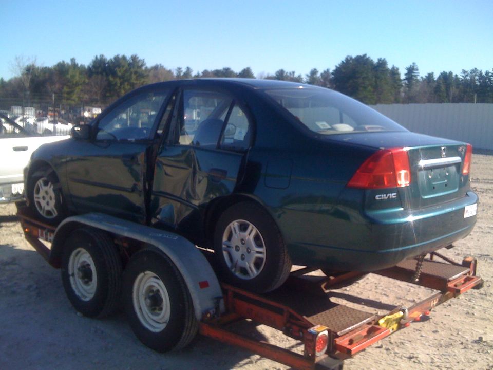 Green Honda Civic on a trailer with collision damage to the doors