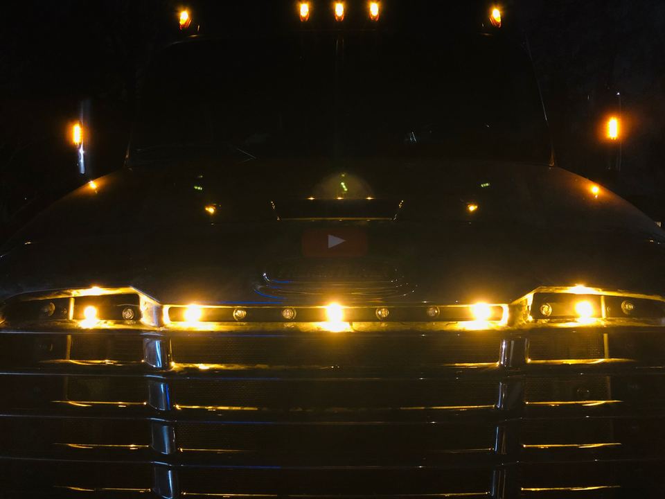 Amber LED lights glowing along a semi-truck hood line at night