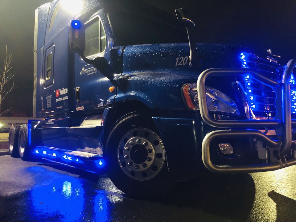 Blue semi-truck at night with blue LED lights along the side skirt and grille